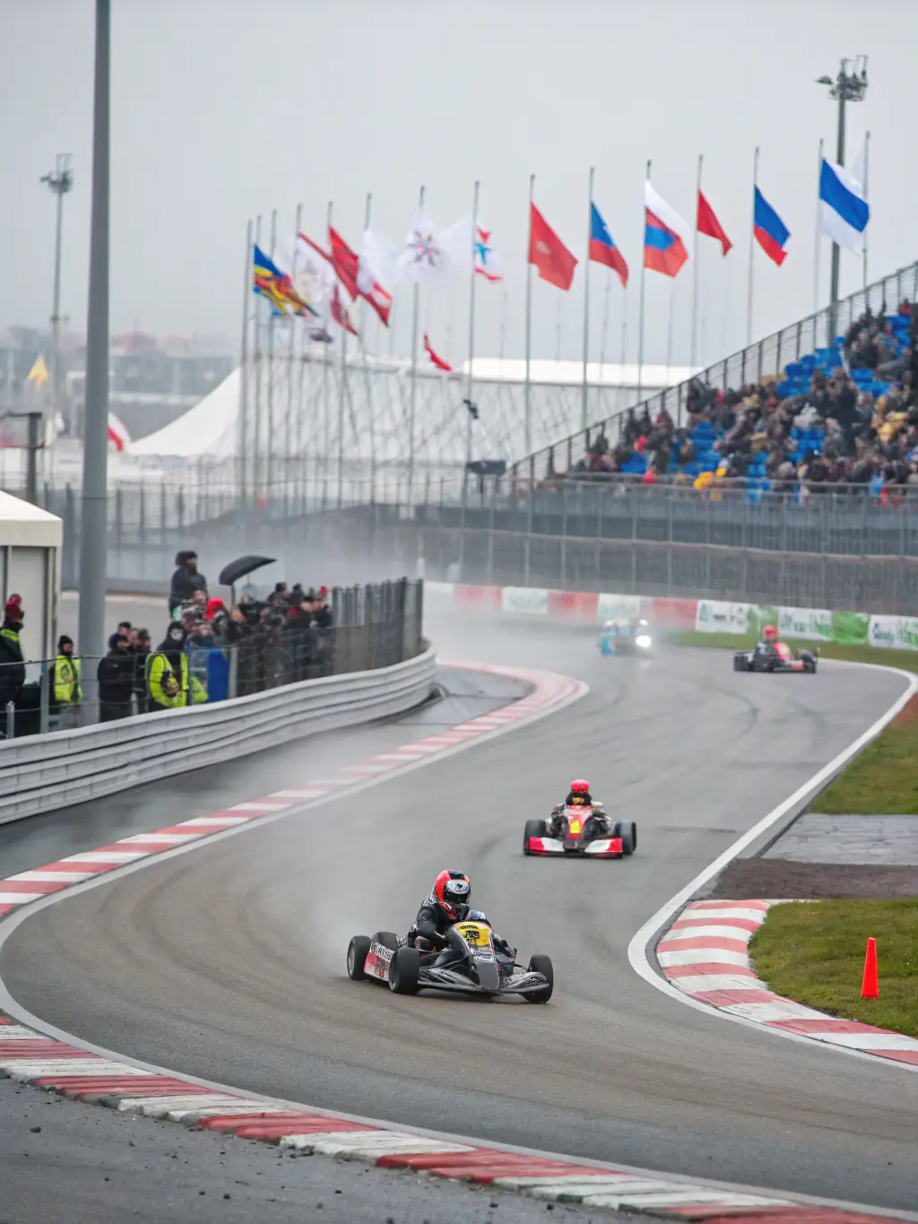 A high-speed go-kart race with participants wearing helmets and racing suits, showcasing the competitive spirit and safety measures of NOAH RACING CONCEPT's go-karting program.